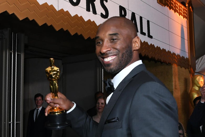 Kobe Bryant enters the Governor's Ball, holding his Academy Award.